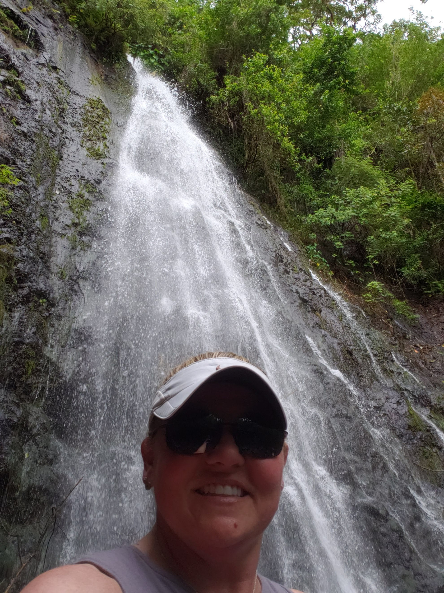 Tiffany Watt standing beneath a waterfall in the Hawaiian rainforest