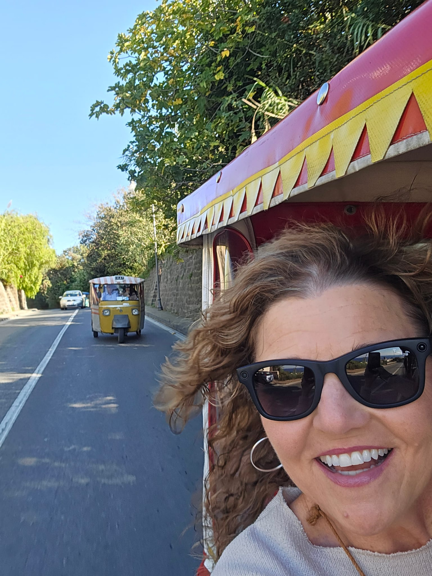 Tiffany Watt riding in a colorful tuk-tuk along an Italian coastal road