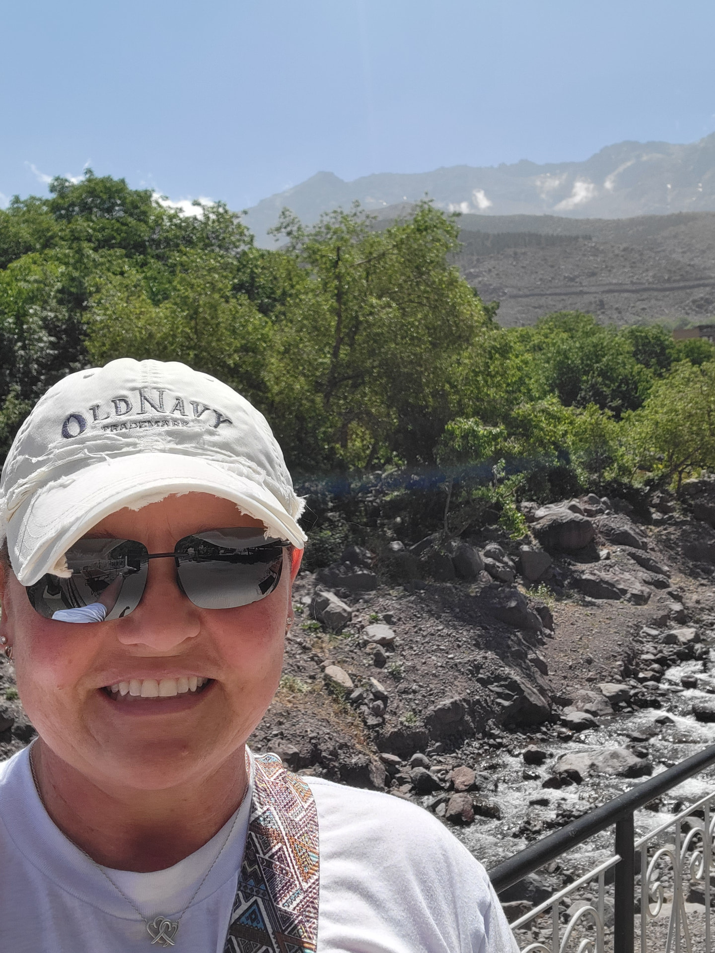 Tiffany Watt on a trail in the Atlas Mountains with peaks and a mountain stream behind her