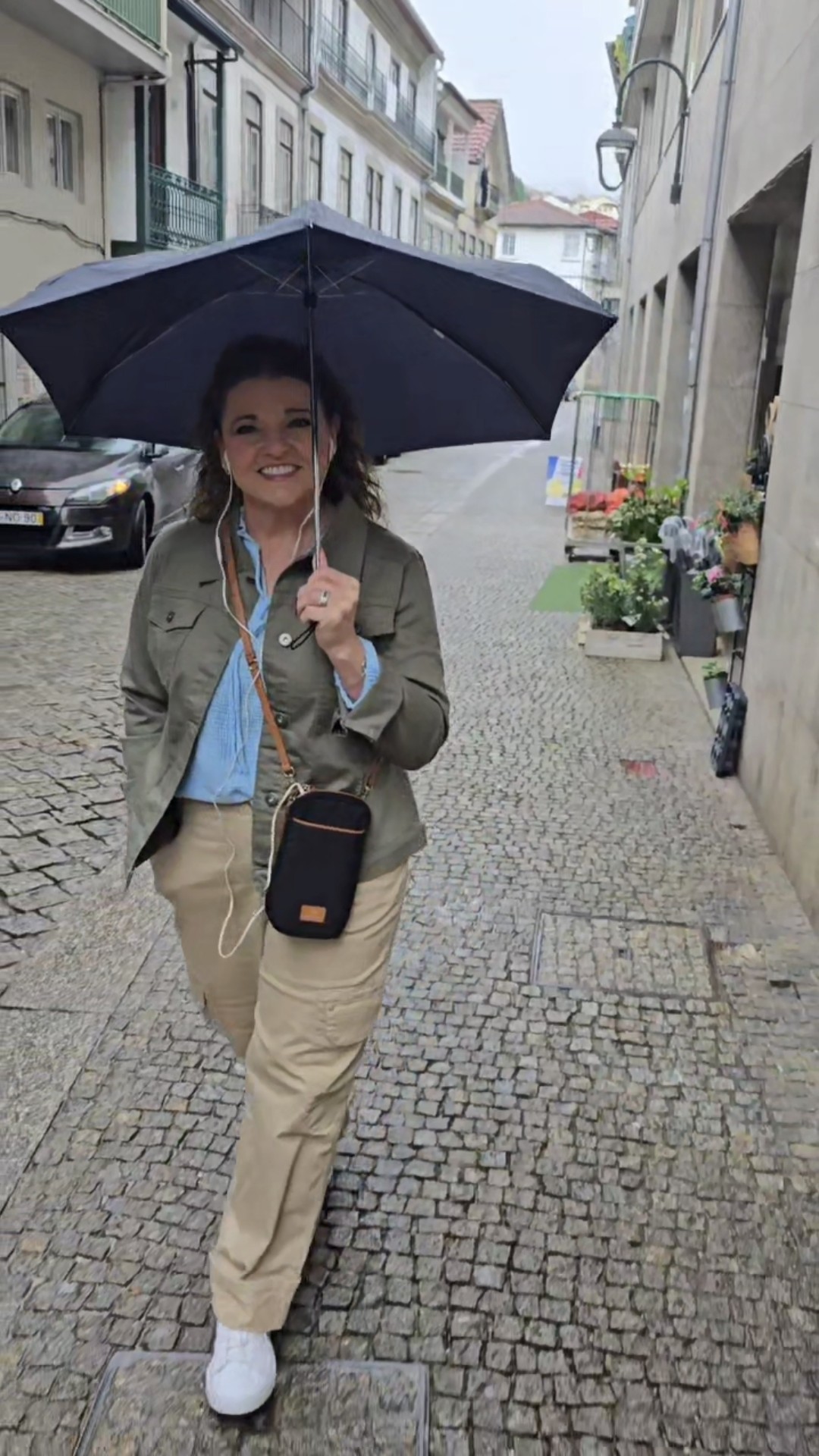 Tiffany Watt walking a cobbled Portuguese street under an umbrella